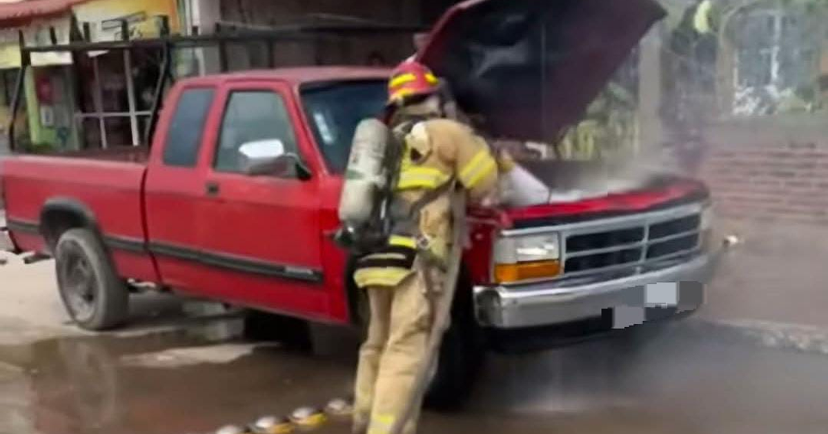 Bombero extinguiendo un incendio en el motor de una camioneta roja