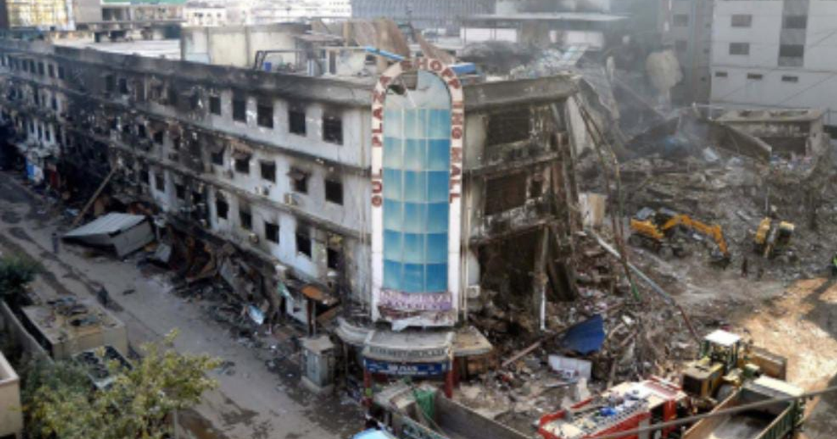 Edificio del centro comercial Gul Plaza dañado tras un incendio en Karachi, con escombros y equipos de construcción presentes.