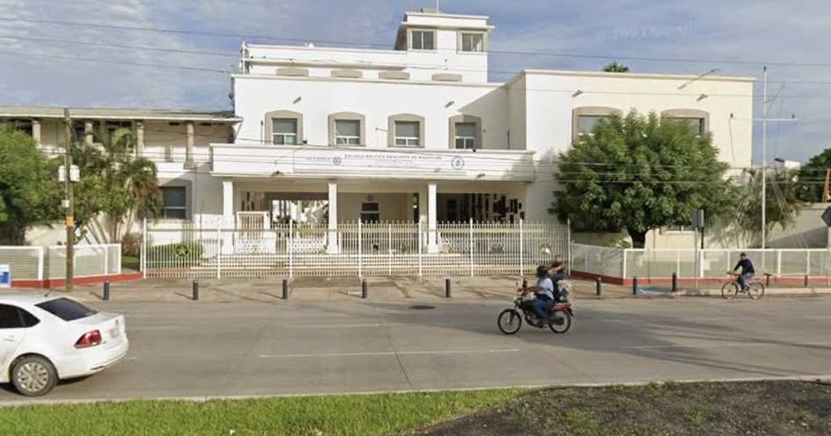 Escuela Náutica Mercante en Mazatlán con ciclistas y vehículos estacionados.