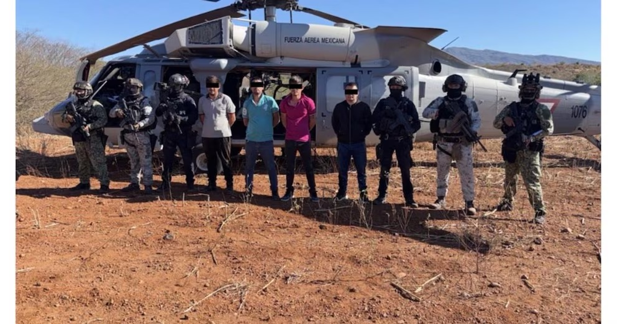 Grupos tácticos y civiles posan frente a un helicóptero militar en Sinaloa durante la detención de "El Mantecas".