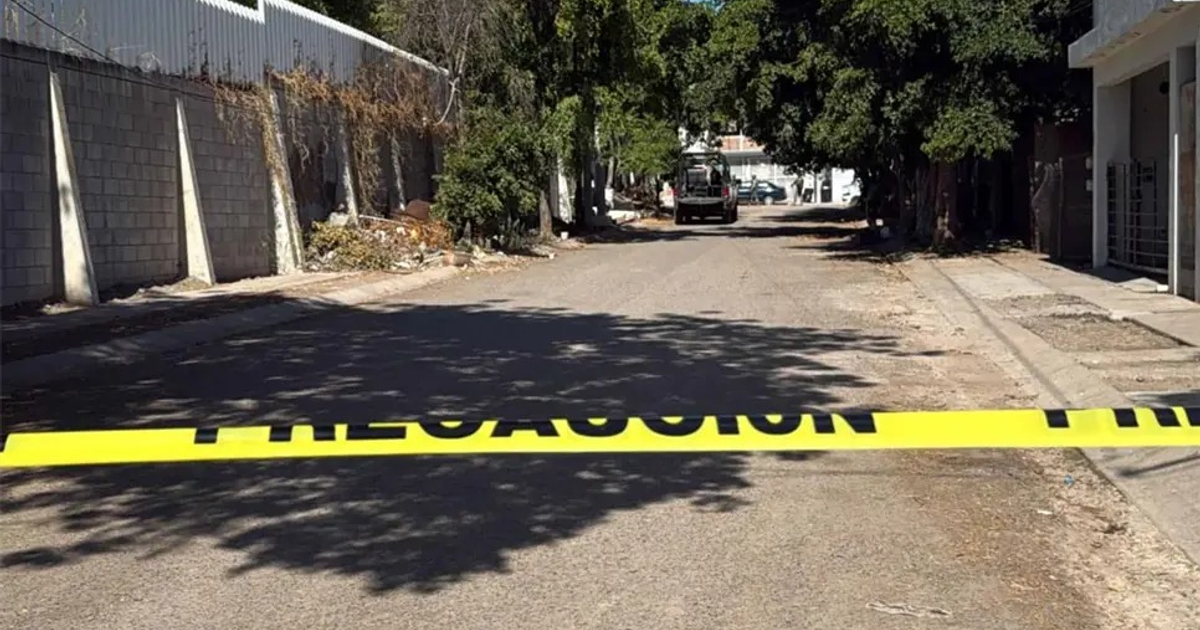 Cinta de precaución bloqueando calle con edificios y vehículo al fondo en colonia Chulavista tras tiroteo.