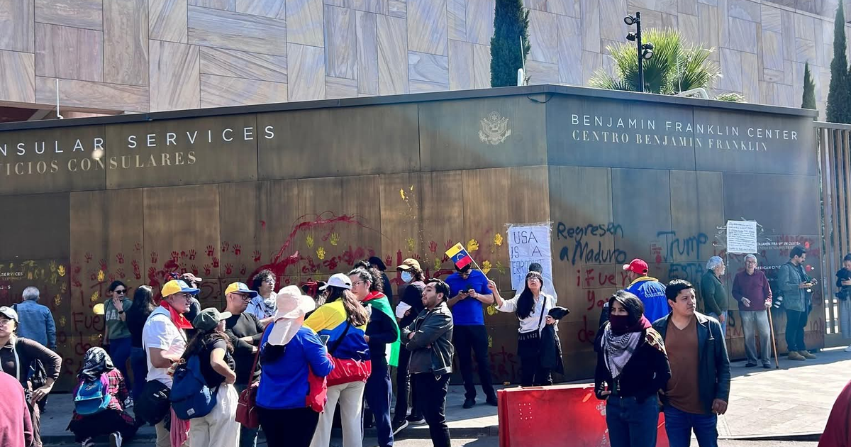 Manifestantes venezolanos protestan frente al Centro Benjamín Franklin con pancartas y grafitis en las paredes.