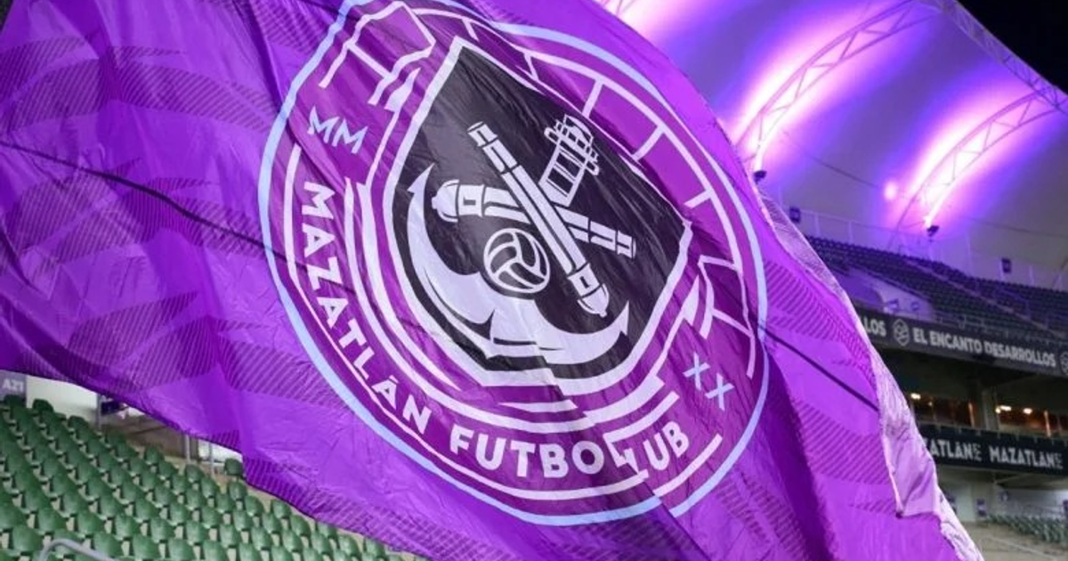 Bandera del Mazatlán FC en un estadio con asientos verdes y luces moradas.