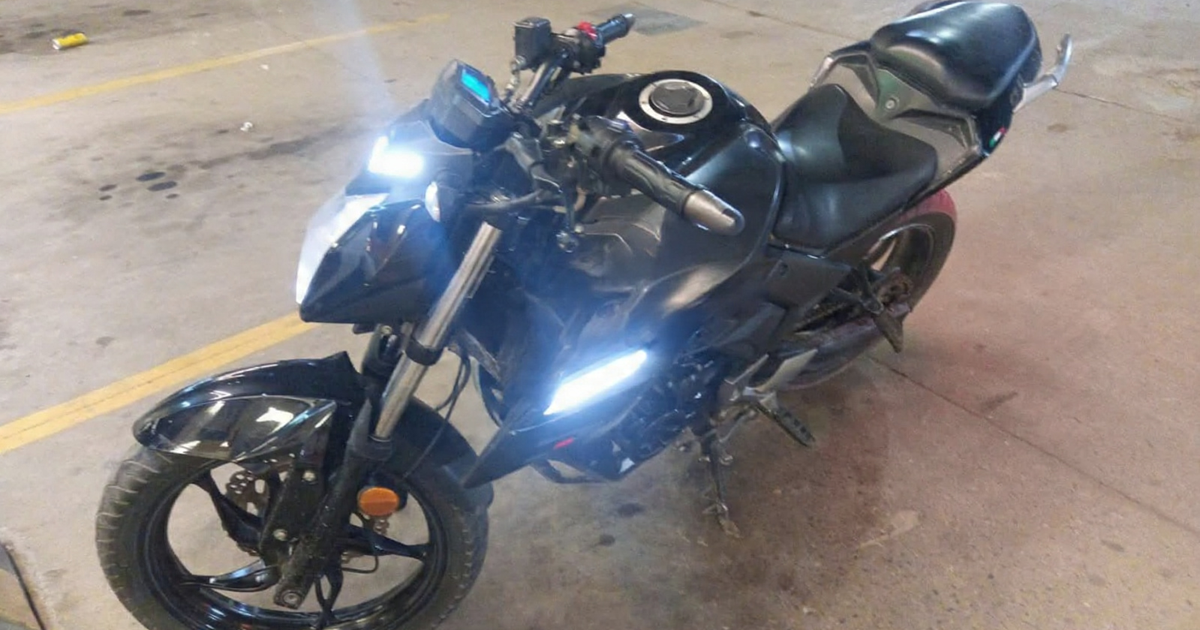 Motocicleta negra encendida estacionada en un garaje con piso manchado y líneas amarillas, vinculada a un hallazgo policial en Mazatlán.