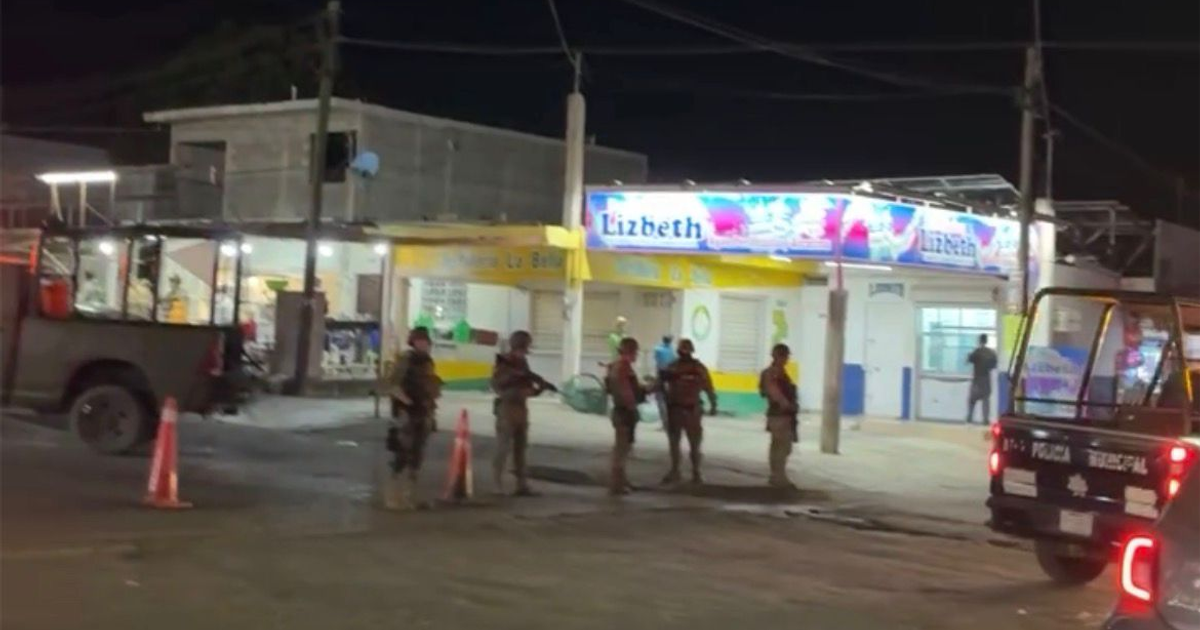 Escena policial nocturna en Culiacán, vehículos policiales y patrulla frente a un comercio.