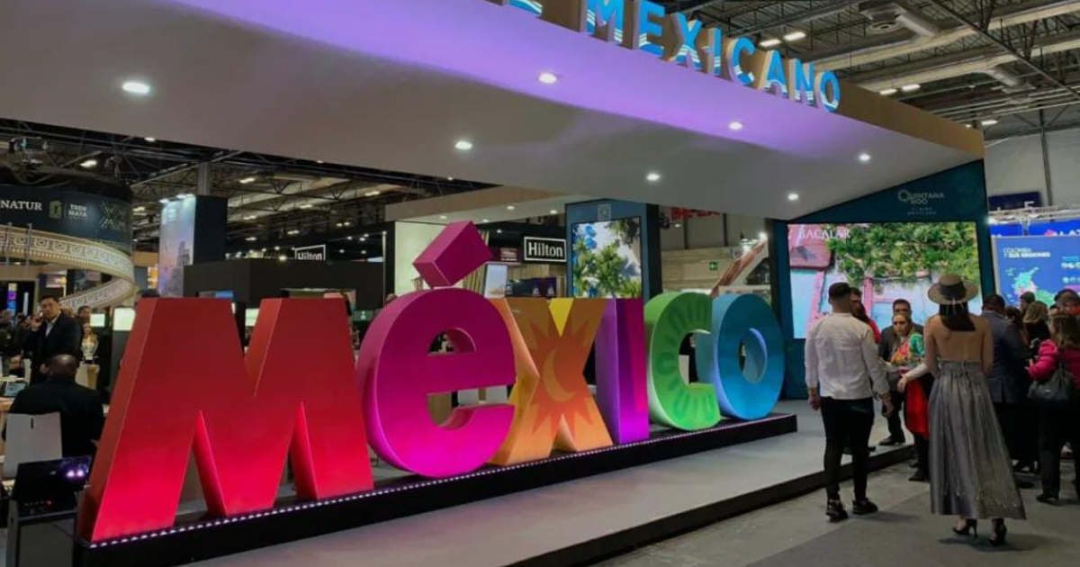 Stand de México en FITUR 2026 con grandes letras coloridas 'México' rodeado de asistentes en un ambiente de feria turística.