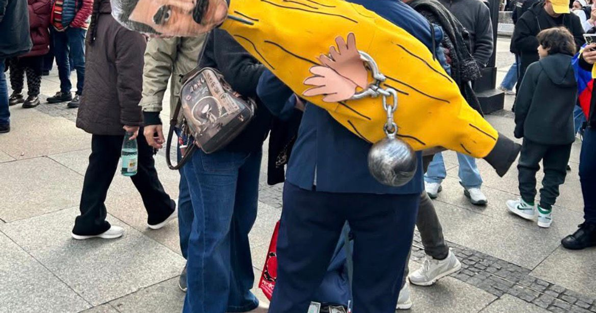 Persona peculiar en protesta en Madrid sosteniendo objeto de forma de banana.