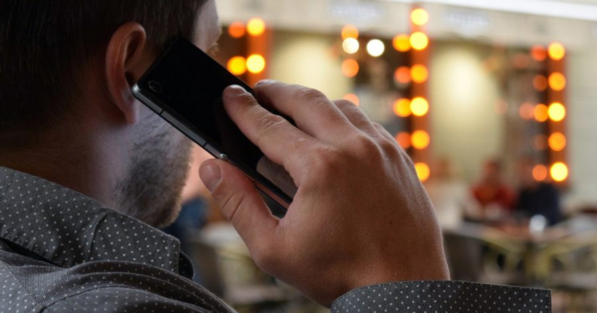 Persona sosteniendo un teléfono móvil en un ambiente con luces brillantes, México 2026.