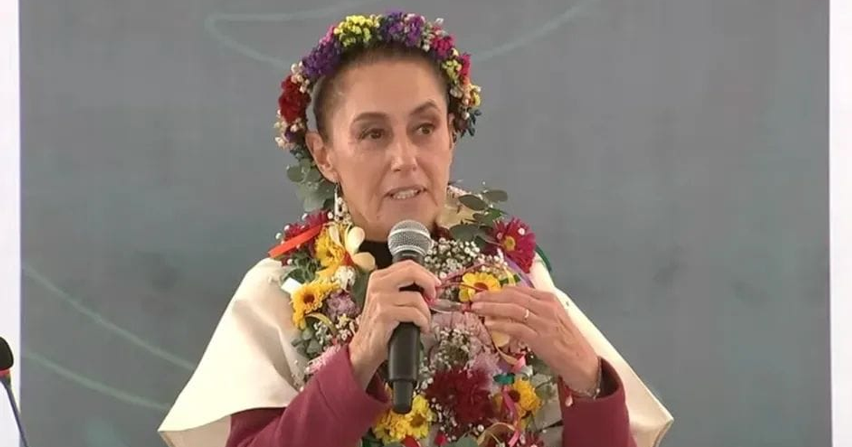 Claudia Sheinbaum hablando en un evento público decorada con flores y diadema, exigiendo disculpas históricas de España.