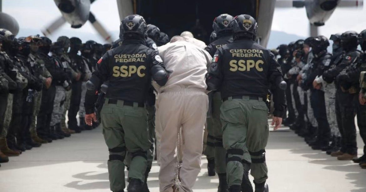 Agentes de seguridad escoltan a un individuo bajo custodia cerca de un helicóptero durante un traslado aéreo desde El Altiplano.