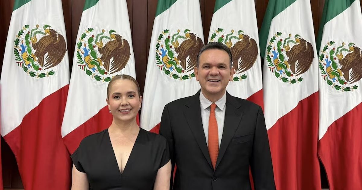 Dos personas frente a banderas mexicanas en un evento