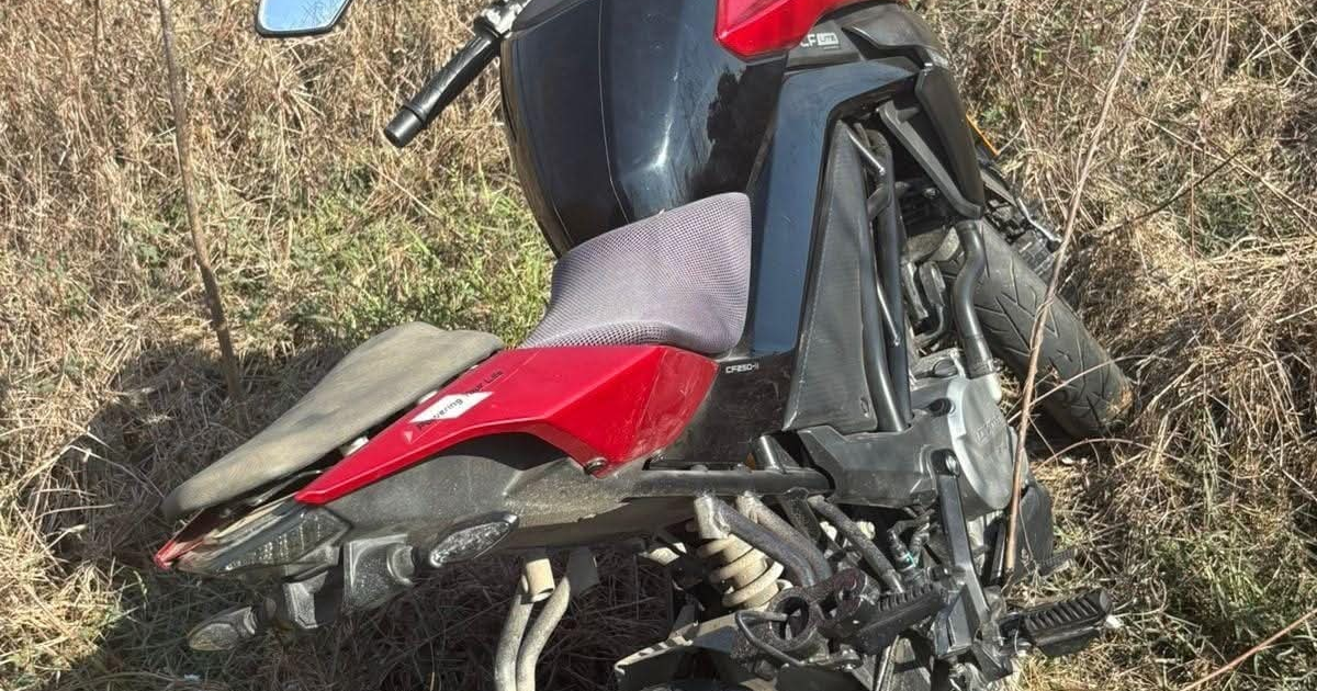 Motocicleta negra y roja abandonada en el campo.